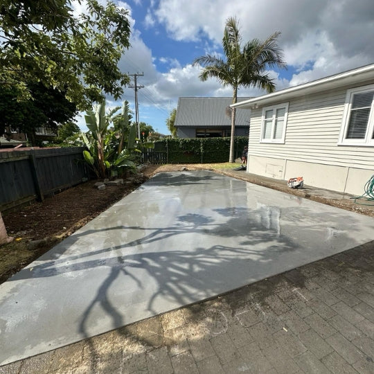 New plain concrete driveway in front of a cream weatherboard Auckland house