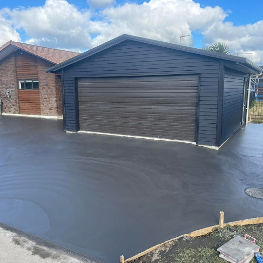 Plain concrete driveway apron in front of a large blue garage shed