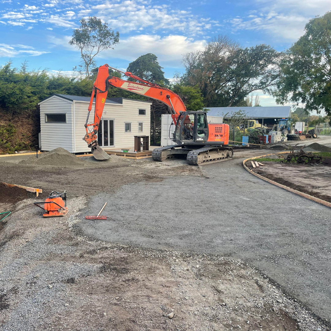 Excavator carrying out earthworks and site preparation beside an Auckland house