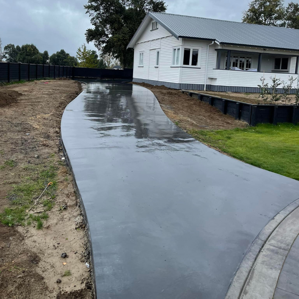 Newly poured concrete driveway curving to a white villa during landscaping