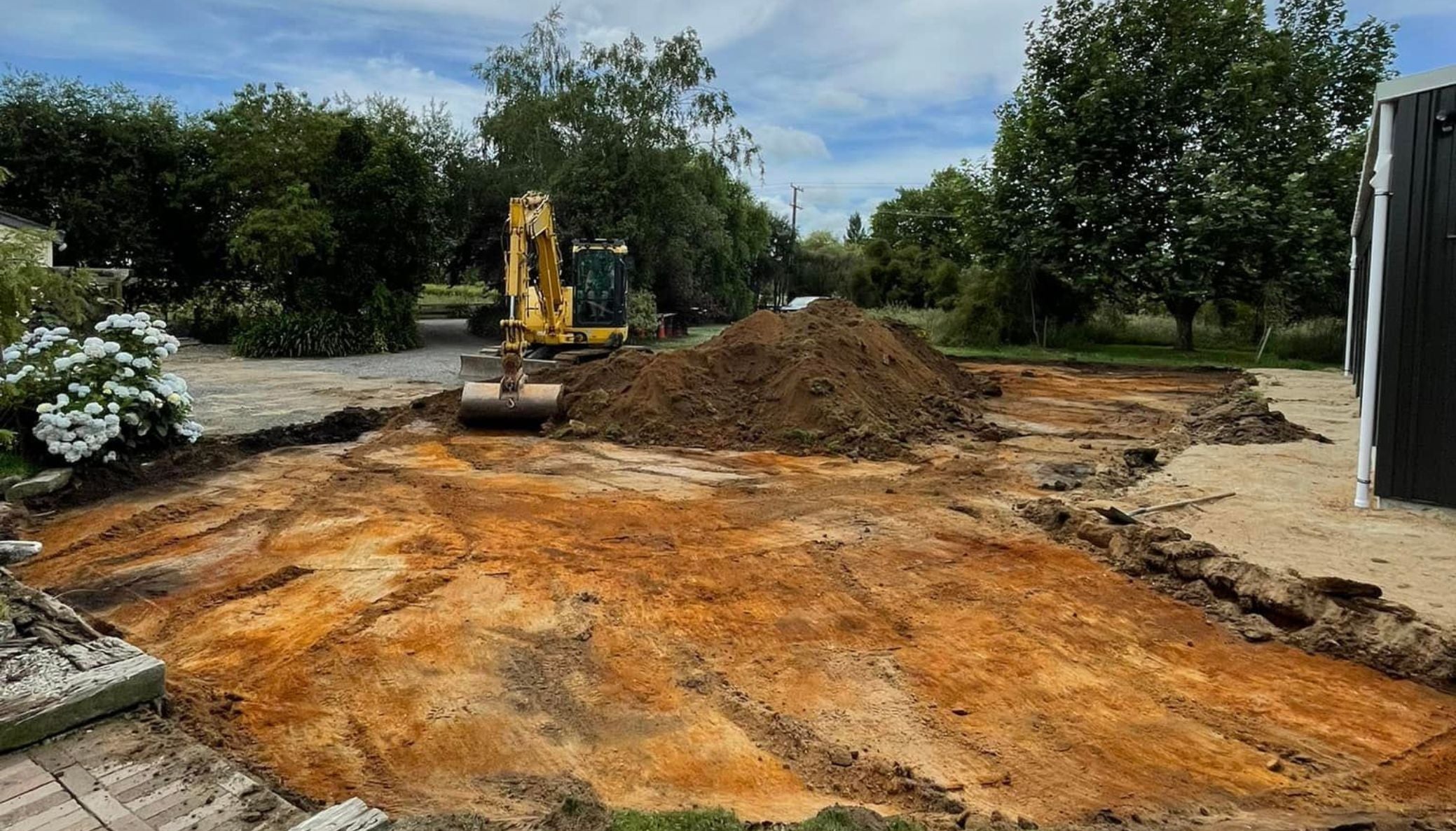 Excavator moving soil during earthworks on an Auckland property