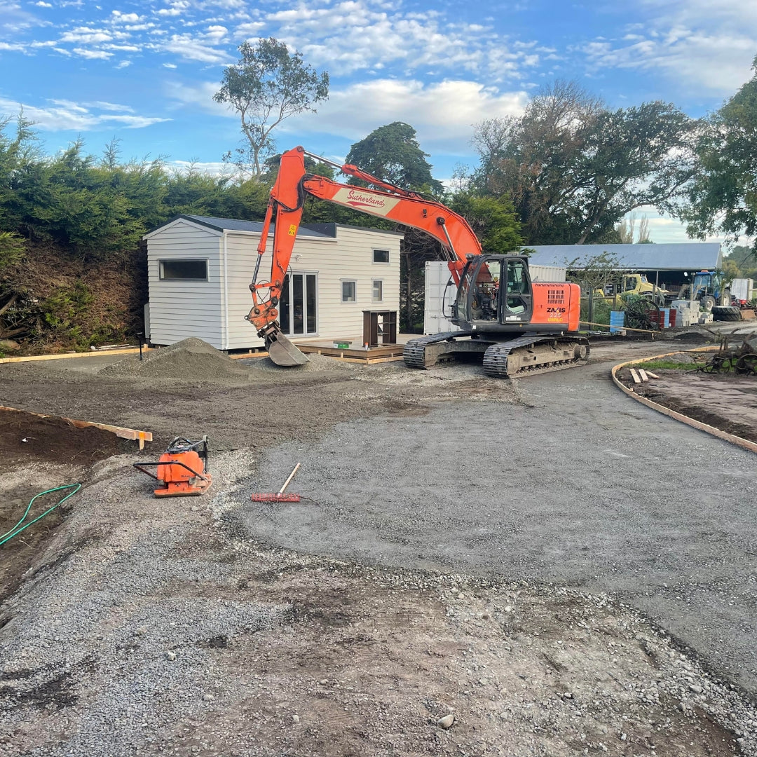 Excavator preparing the ground during earthworks beside an Auckland home