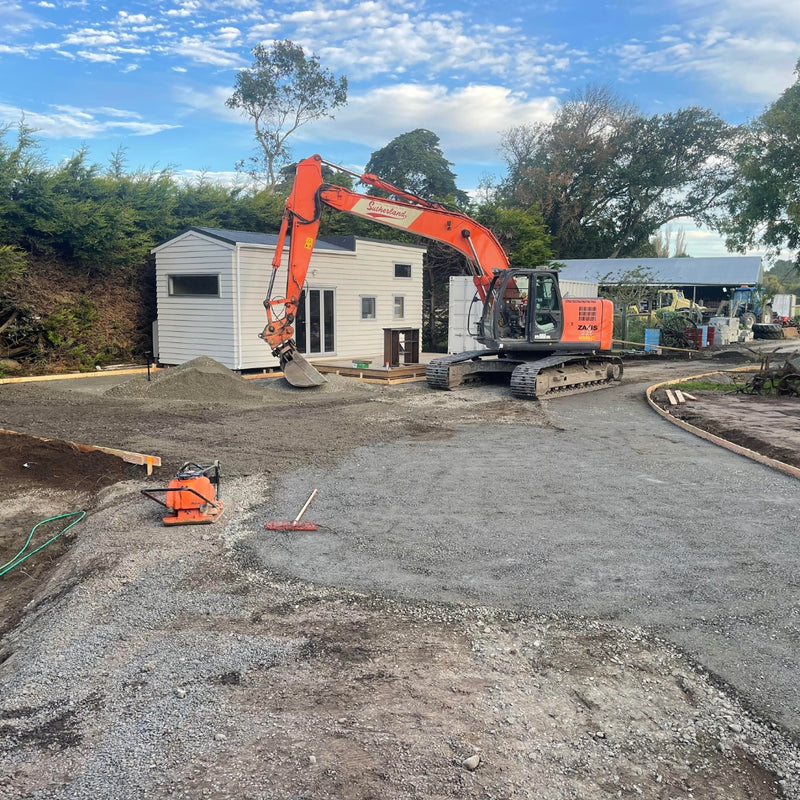 Excavator preparing the ground during earthworks beside an Auckland home