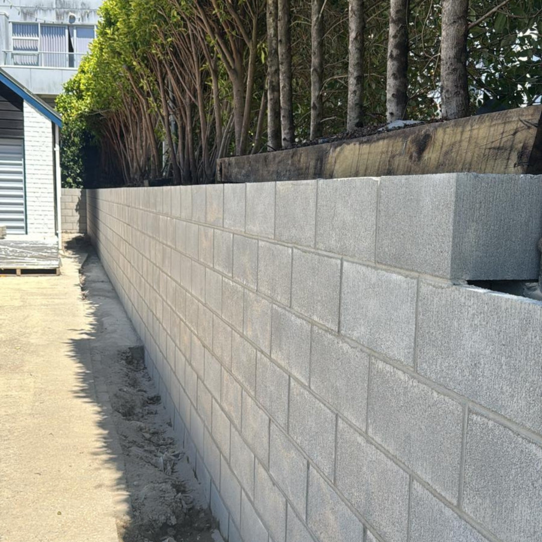 Concrete block retaining wall running along a hedged side path