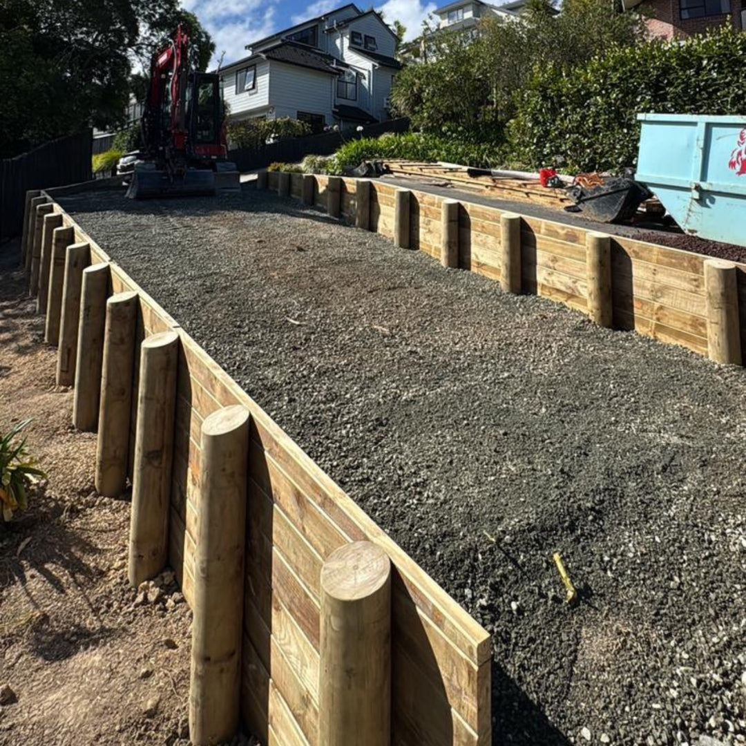 Completed timber pole retaining wall with gravel backfill on a sloped site