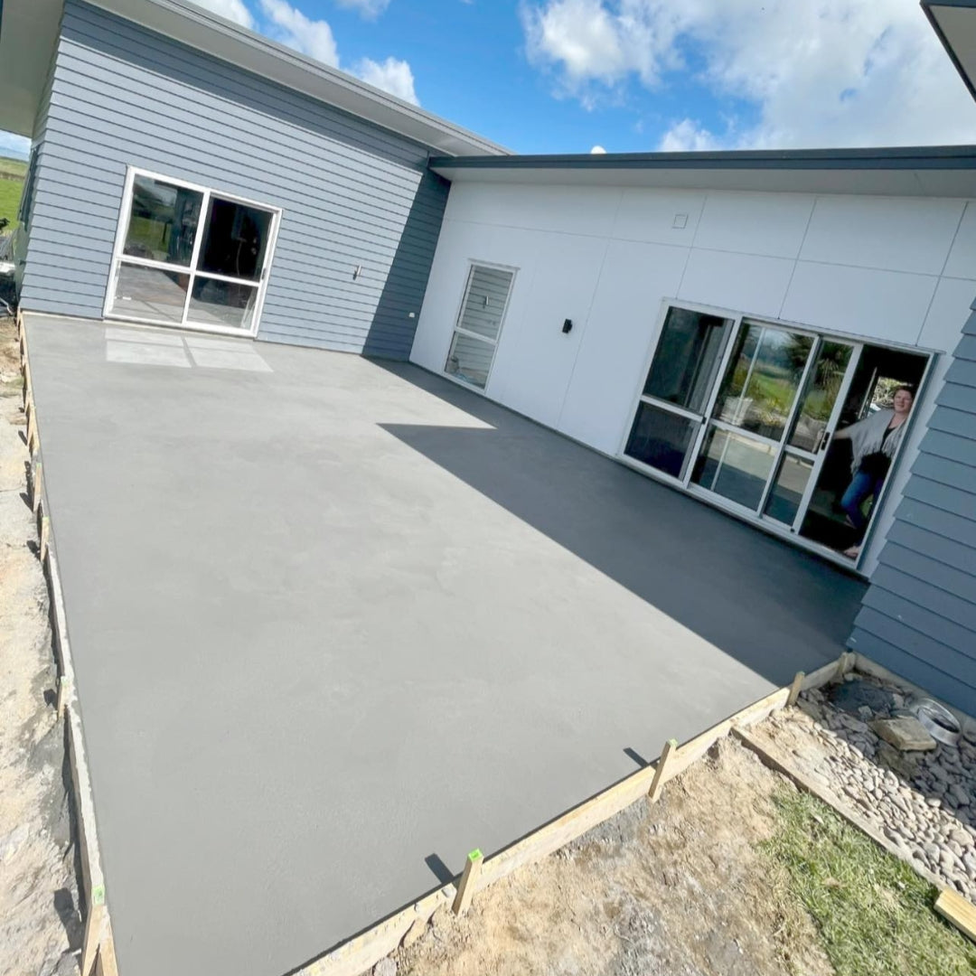Plain concrete patio wrapping around a modern grey Auckland home