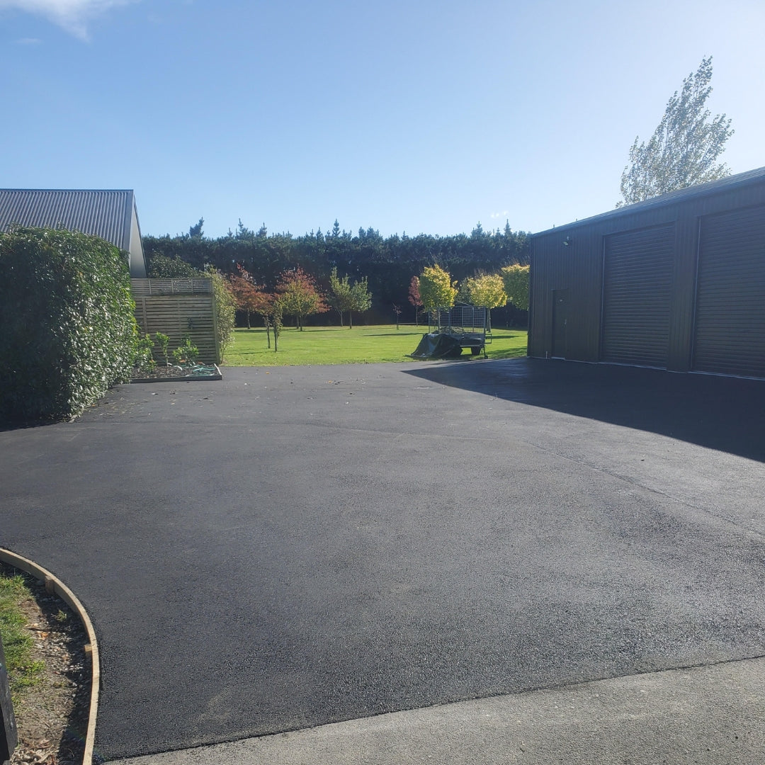 Asphalt driveway beside a dark shed, installed by Slab Lab in Auckland