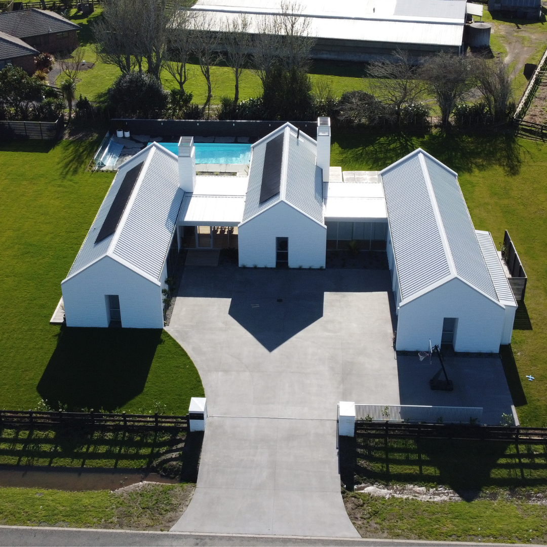 Aerial view of an Auckland home with a concrete driveway and pool