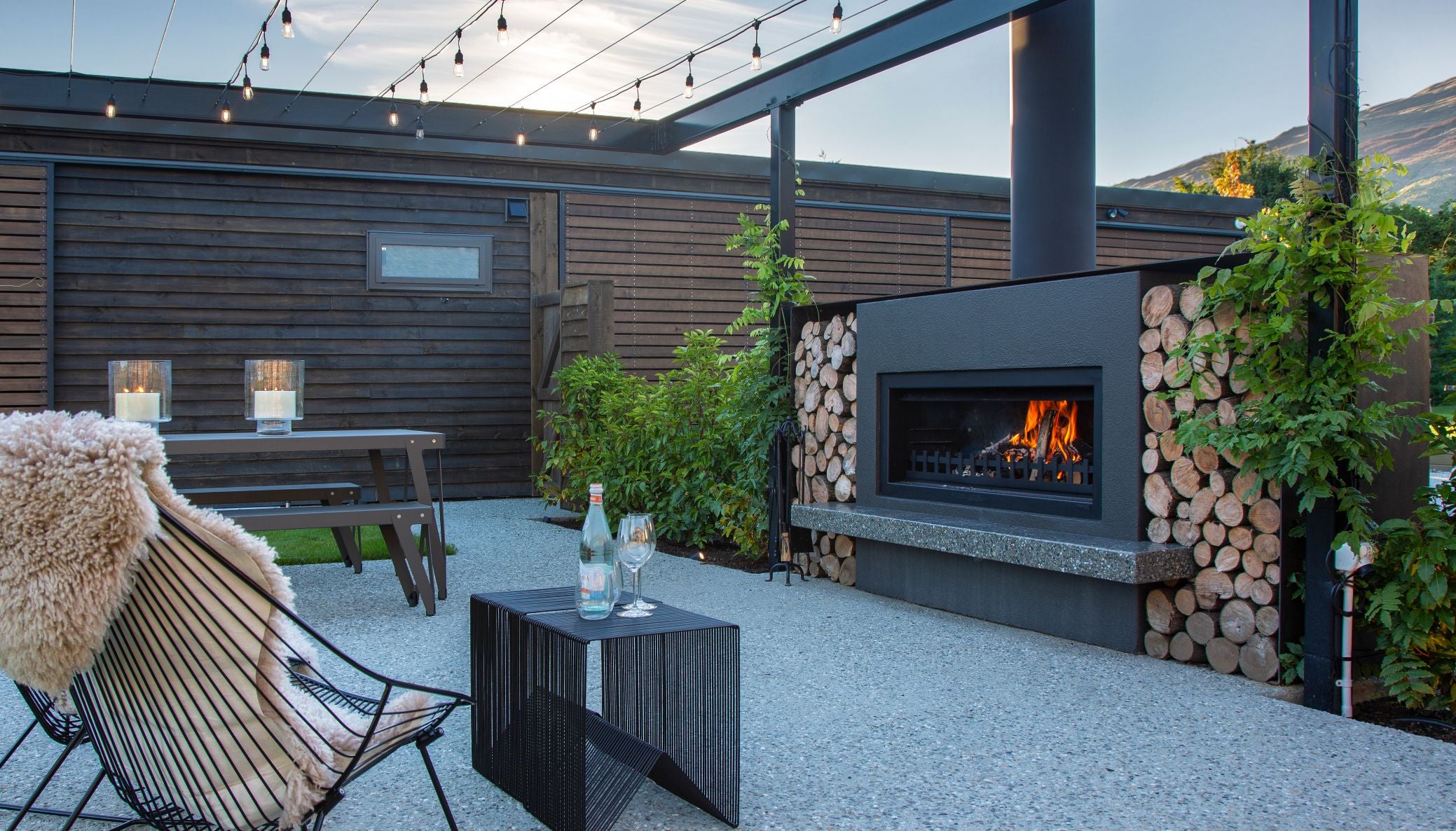 Concrete patio with an outdoor fireplace and lounge seating in the evening